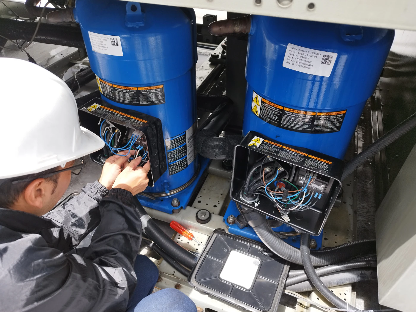 Técnico revisando las conexiones eléctricas de los compresores de un chiller