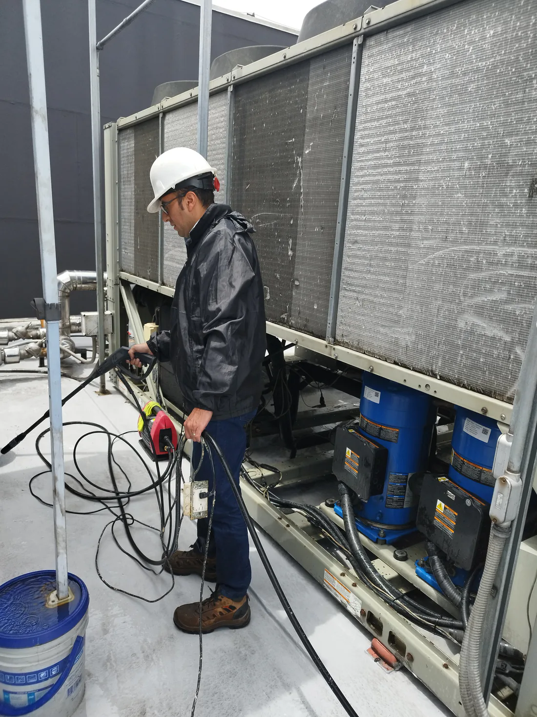 Técnico haciendo mantenimiento a un chiller en la cubierta de un edificio