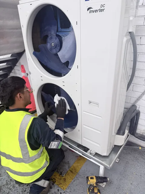 Técnico limpiando la unidad condensadora de un sistema inverter