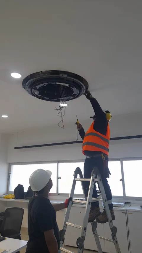 Técnico instalando una unidad cassette circular en una oficina